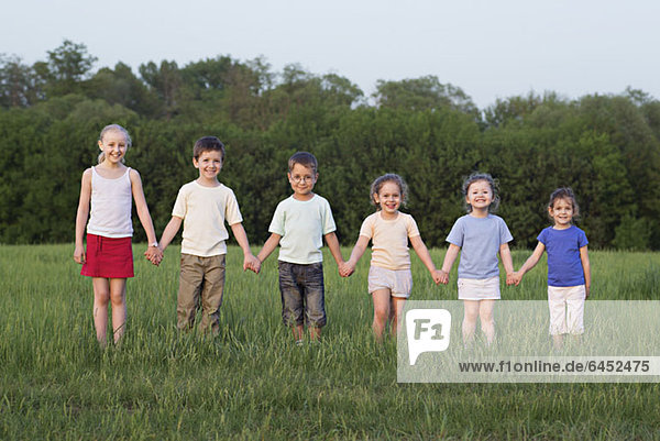 Porträt von Kindern  die auf einem Feld Händchen halten