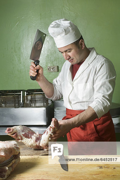 Ein Metzger hackt Fleisch mit einem Hackbeil