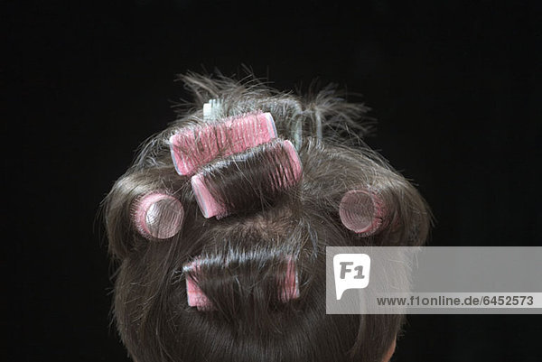 Rückansicht einer Frau mit Lockenwicklern im Haar