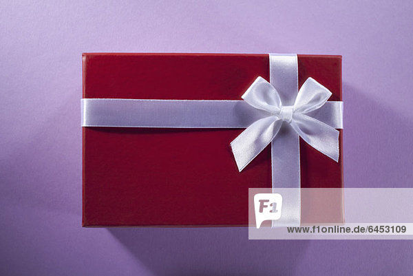 Ein Geschenk verpackt in rotes Papier und weißes Band und Schleife