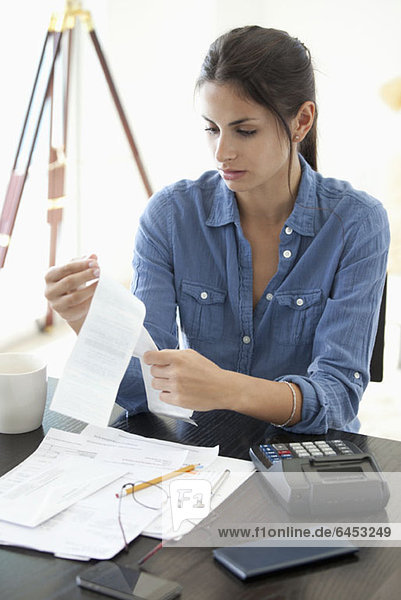 Woman at desk looking at receipts