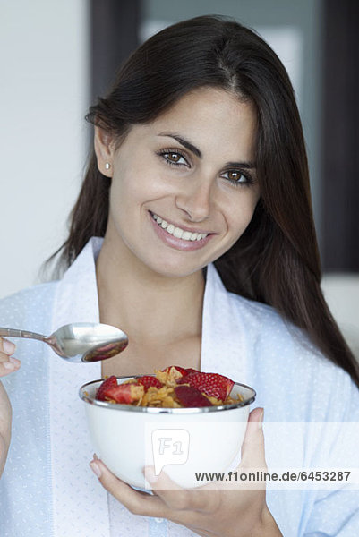 Woman with breakfast bowl of cereal and strawberries