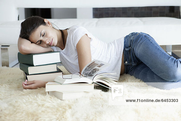 Frau schläft auf ihren Büchern