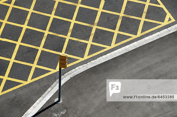 Gelbe Linien auf der Straße zur Markierung des Halteverbots in der Nähe einer roten Ampel/Kreuzung