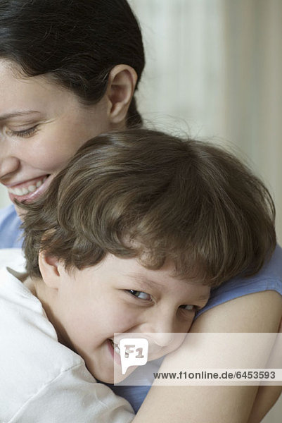 Eine Mutter und ihr kleiner Sohn umarmen und lachend