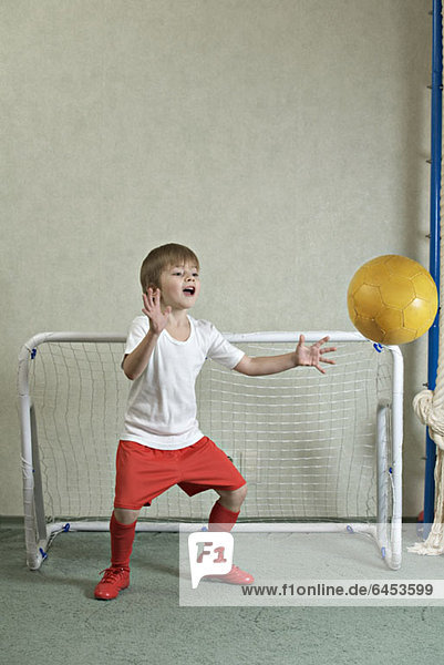 Ein Junge verteidigt ein Tor,  während ein Ball auf ihn zufliegt.