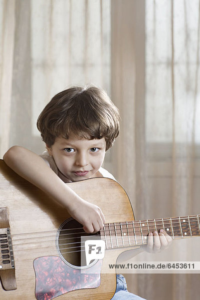 Ein kleiner Junge hält eine Akustikgitarre.