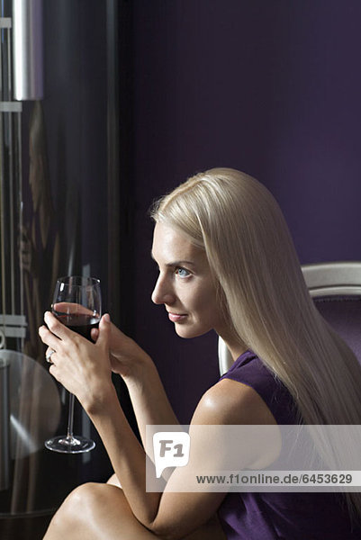 A beautiful young woman holding a glass of red wine