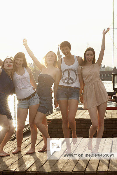 Five young female friends celebrating on a jetty  Spree River  Berlin  Germany