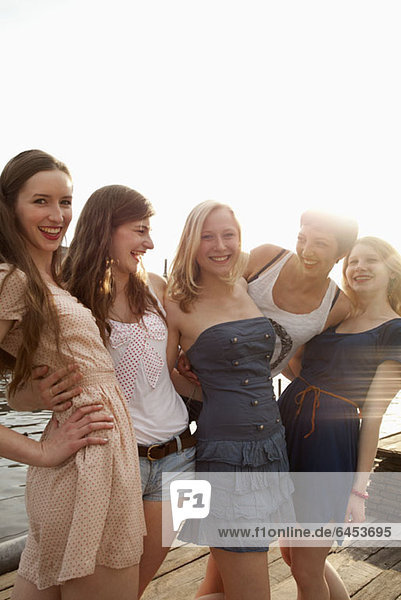 Five young female friends together on a jetty