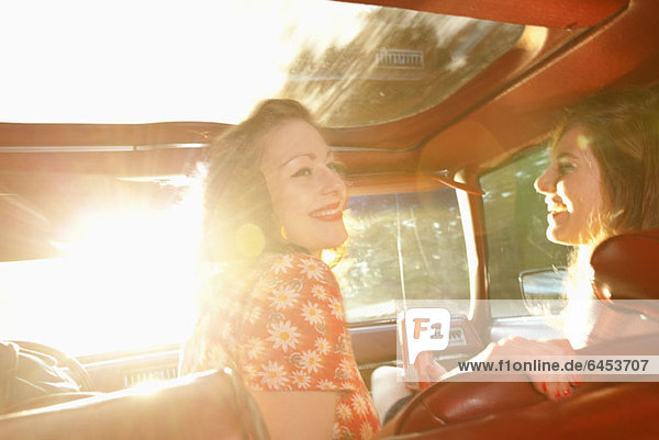 Two rockabilly women having fun in the front seat of a vintage car
