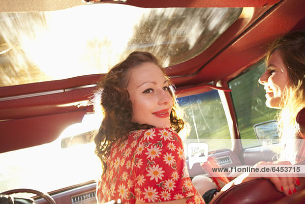 Two rockabilly women having fun in the front seat of a vintage car