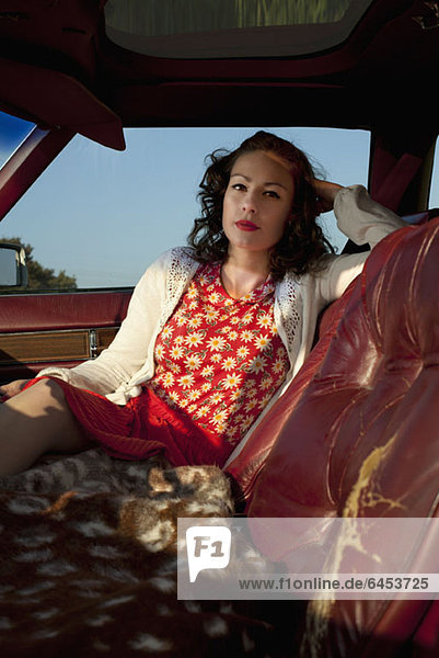 A pretty rockabilly woman sitting in the passenger seat of a vintage car