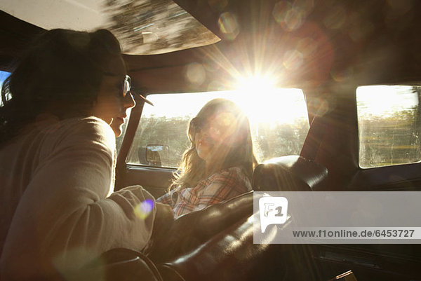 Two serene rockabilly women in the front seat of a vintage car