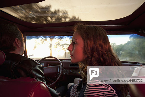A rockabilly couple in the front seat of a vintage car