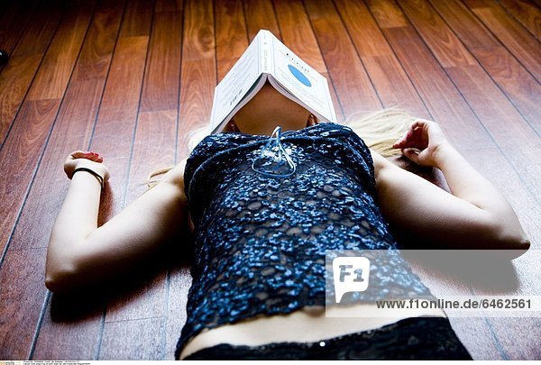 Eine junge Frau ist beim lesen auf dem Fussboden eingeschlafen