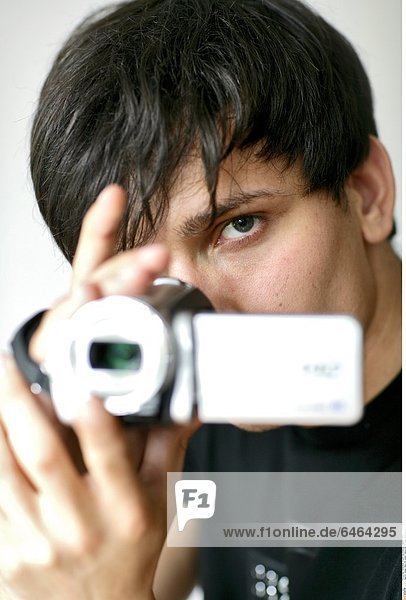 Junger Mann mit einem Camcorder *** Local Caption ***