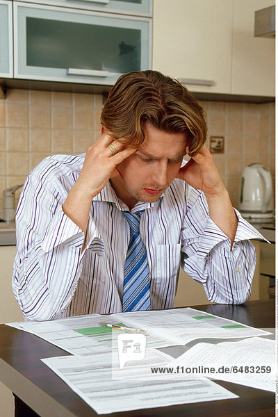 1217891 indoor flat kitchen man 35-40 mature whitey sit chemise stripe striped tie close up paper papers document documents tear tax return tax returns fill account for accounts worry stress tiredness think base hand hands head vertical