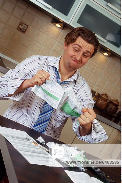1217902 indoor flat kitchen man 35-40 mature whitey sit tie chemise stripe striped close up angry stress paper papers document documents tear tax return tax returns fill account for accounts calculate destroy emotions mime vertical
