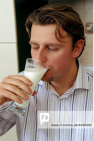 1222047 indoor flat kitchen young man dark haired 25-30 shirt stripe stripes hold milk glass drink dairy product close up vertical