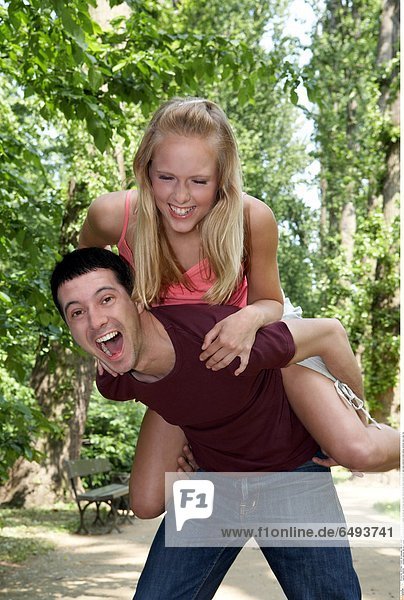 1240028 outodoor summer day park people man young 20-25 boy couple woman girl blonde long dark haired blouse black blouses pink rest relax embrace smile smiling vertical carry play fun