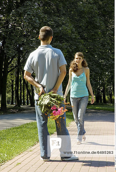 1241639 outdoor summer day people woman 20-25 girl young brunette long haired blouse blue stripe stripes striped vertical rest relax park portrait couple man boy dark haired smile smiling hold flower flowers back