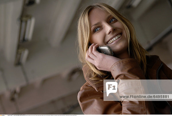 1241839 indoor studio people woman young 20-25 blonde long haired portrait close up smile smiling jacket leather brown talk conversation telephone cell cellphone cellular telecommunication communication horizontal mobile phone