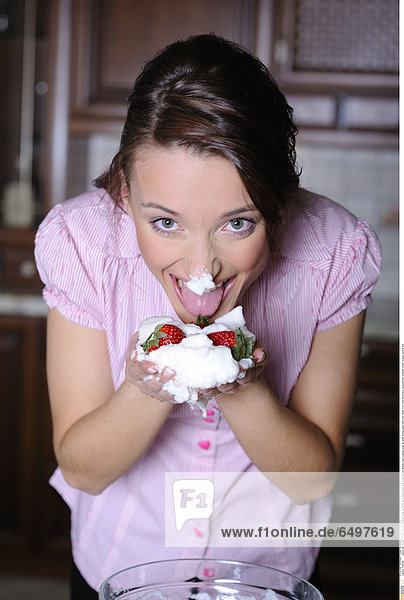 1248264 indoor flat kitchen people woman brunette close up 20-25 girl young blouse pink stripe stripes striped cook cooking close up smile smiling basin hand hold hands fruit fruits strawberry strawberries whipped cream sweets vertical eat