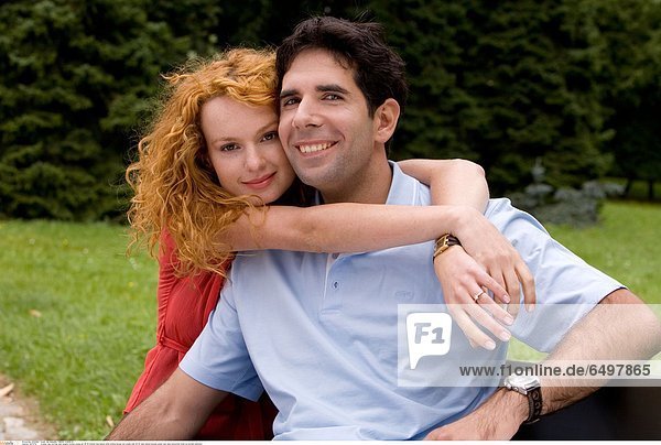 1247279 outdoor day summer park people woman young girl 20-25 blonde long haired smile smiling blouse red couple man 25-30 dark haired blouses green rest relax horizontal close up portrait embrace