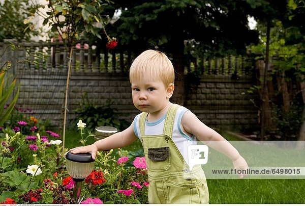1247031 outdoor day summer people child boy 0-5 fair haired blouse white trousers yellow horizontal garden flower flowers