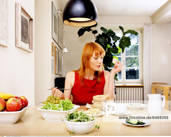1246524 indoor flat kitchen people woman young girl 20-25 blonde fringe rest relax blouse red close up portrait eat dinner breakfast grape grapes fruit fruits vegetable lettuce coffee tea cup slice slices bread cucumber horizontal cress apple apples hand hold fork