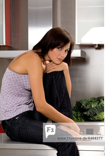 1247239 indoor flat kitchen people woman young 25-30 brunette close up hand hold blouse violet vertical smile smiling sit table trousers foot feet barefoot
