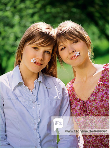 1248179 people woman women girl girls sister sisters friend friends 15-20 20-25 blonde blondes plant plants hold mouth flower flowers outdoor garden summer orchard vertical