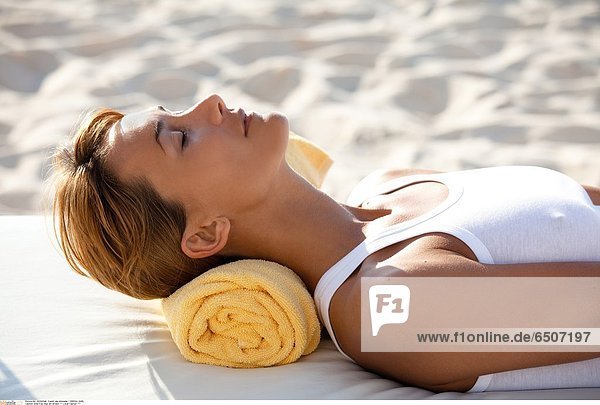 Eine Frau liegt am Strand *** Local Caption ***