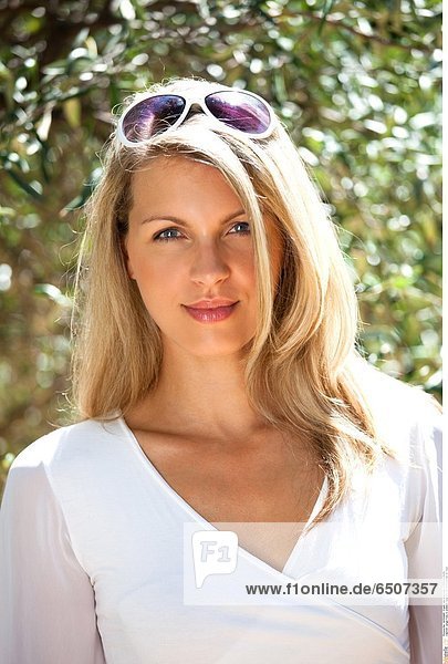 Junge Frau in weißem Oberteil mit Sonnenbrille im Haar