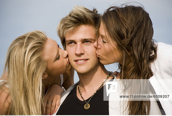Mandatory Credit: Photo by John Powell / Rex Features ( 1041023ci ) Model released - two teenage girls kiss boy on cheeks Various