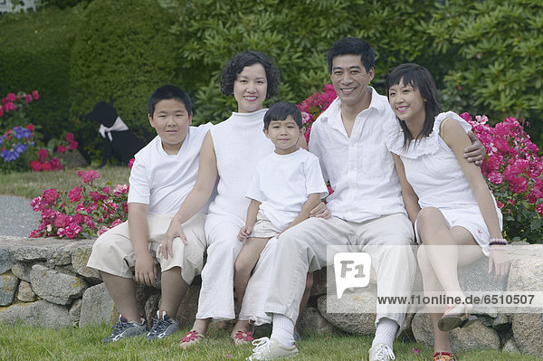 Asian family sitting and smiling outdoors