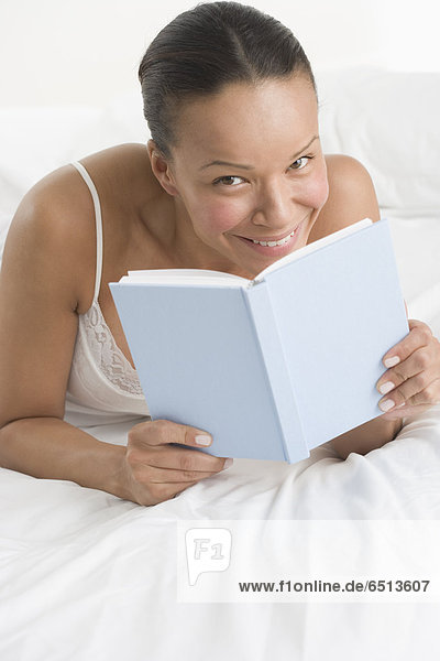 Portrait of woman laying on bed reading book