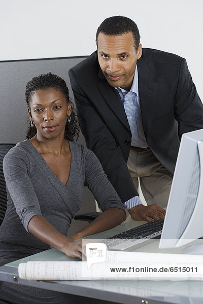 Portrait of man and woman at desk with computer
