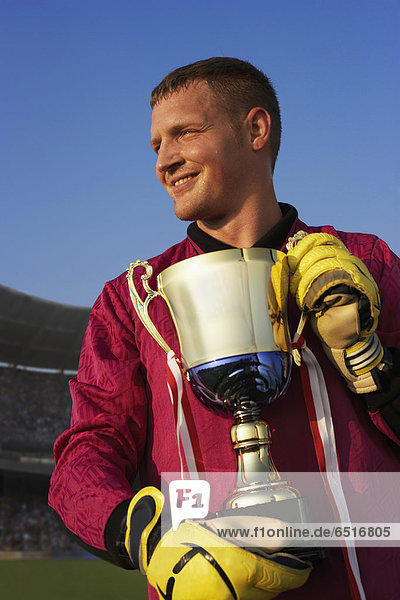 Male goalie triumphantly holding trophy