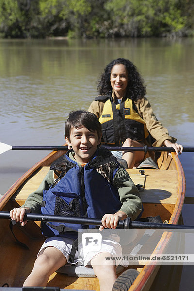 Hispanic mother and son sitting in canoe