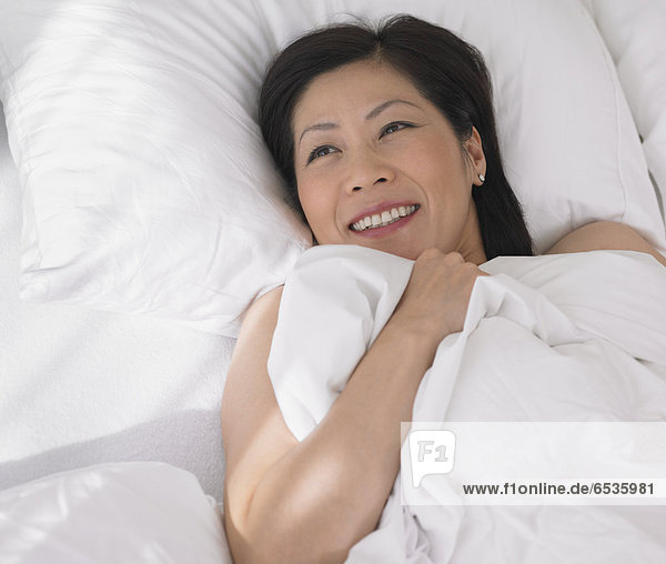 Middle-aged Asian woman laying in bed