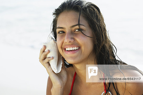 South American woman listening to seashell