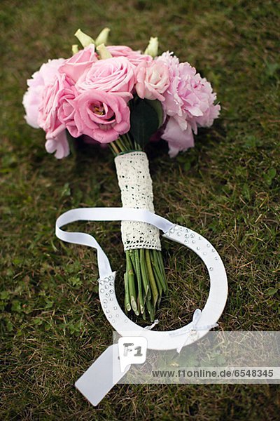Wedding bouquet and horseshoe on grass