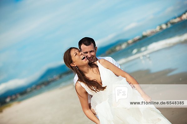 Newlywed couple embracing on beach