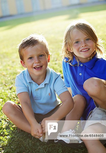 Portrait of two boys sitting on grass