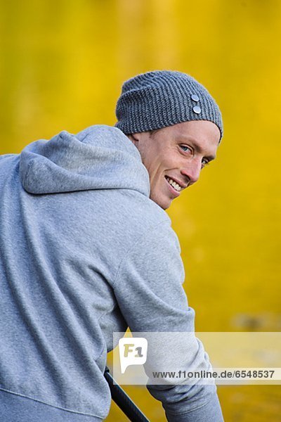 Man in knit cap smiling over shoulder  outdoors