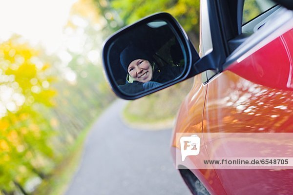 Woman smiling in rear view mirror on country road