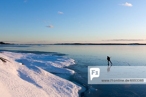 Person ice-skating on frozen lake