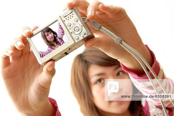 Woman taking a photograph of herself with a digital camera
